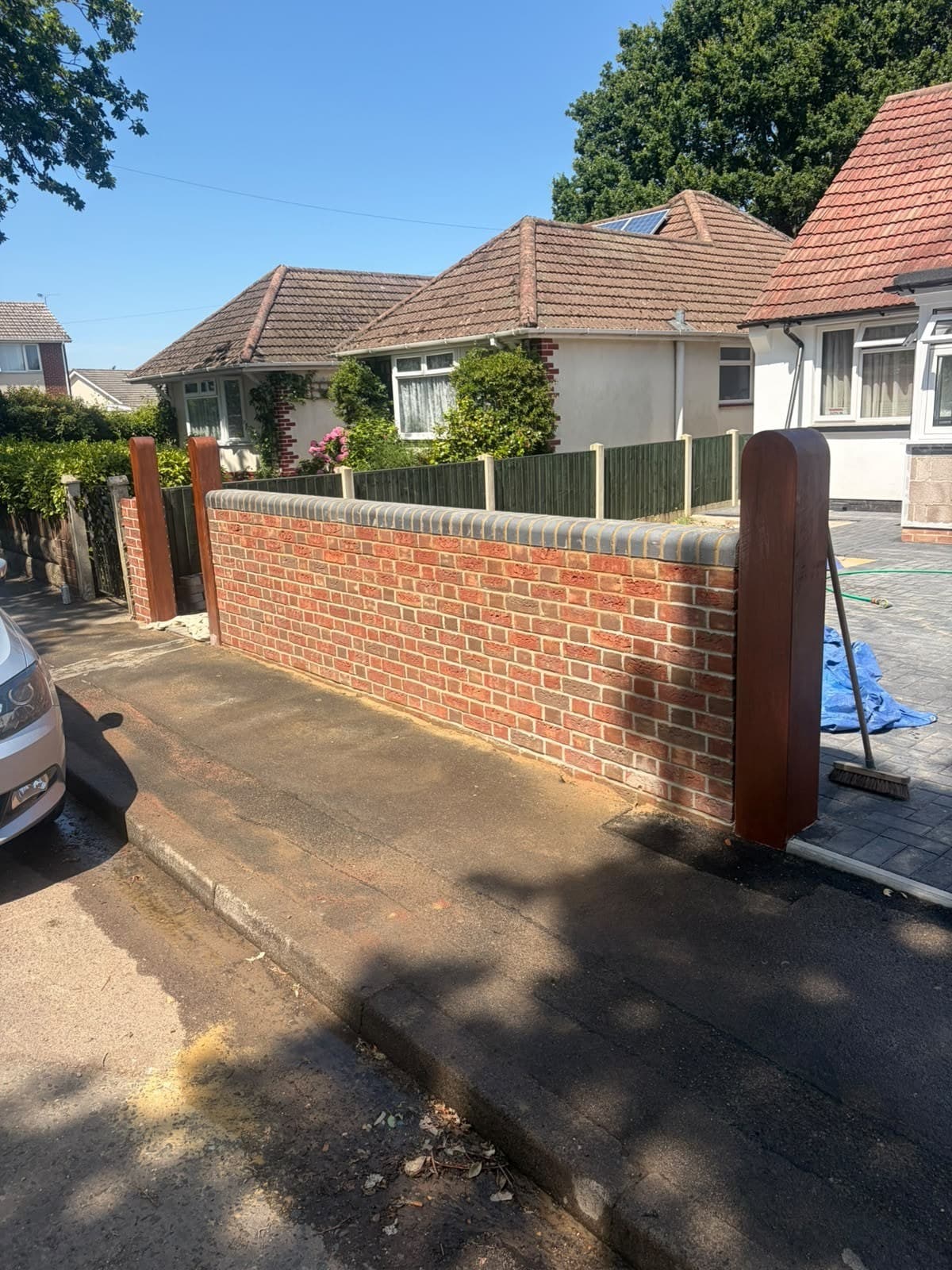 A brick boundary wall with matching gate posts along a driveway
