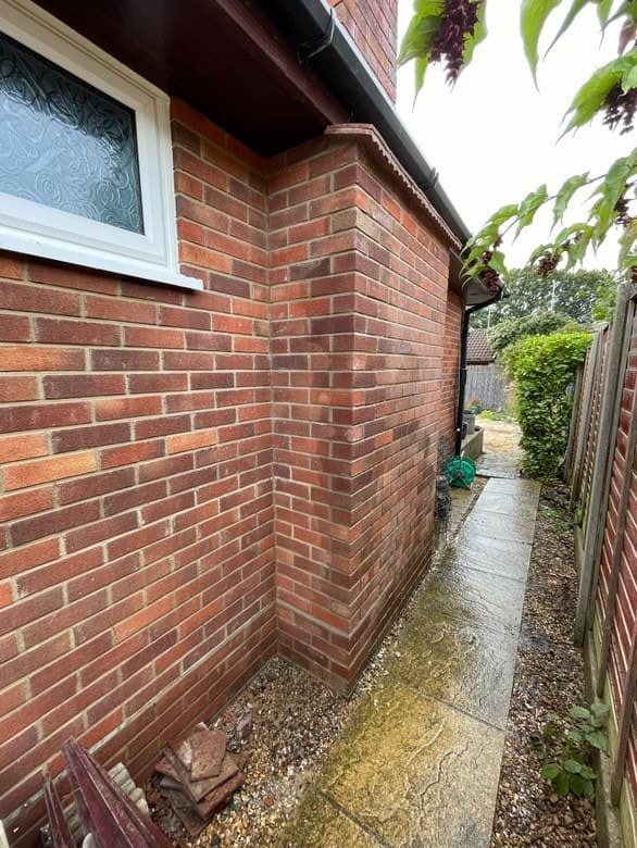 A rebuilt brick corner on a house extension, seen after rain