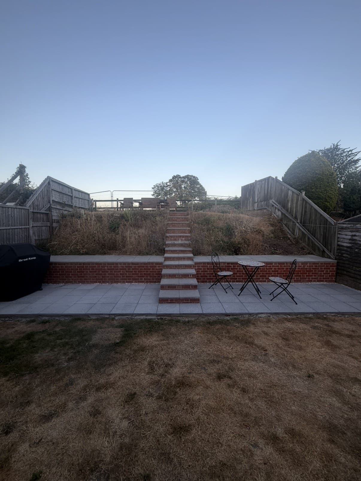 A brick retaining wall with steps up the middle and a new patio in front