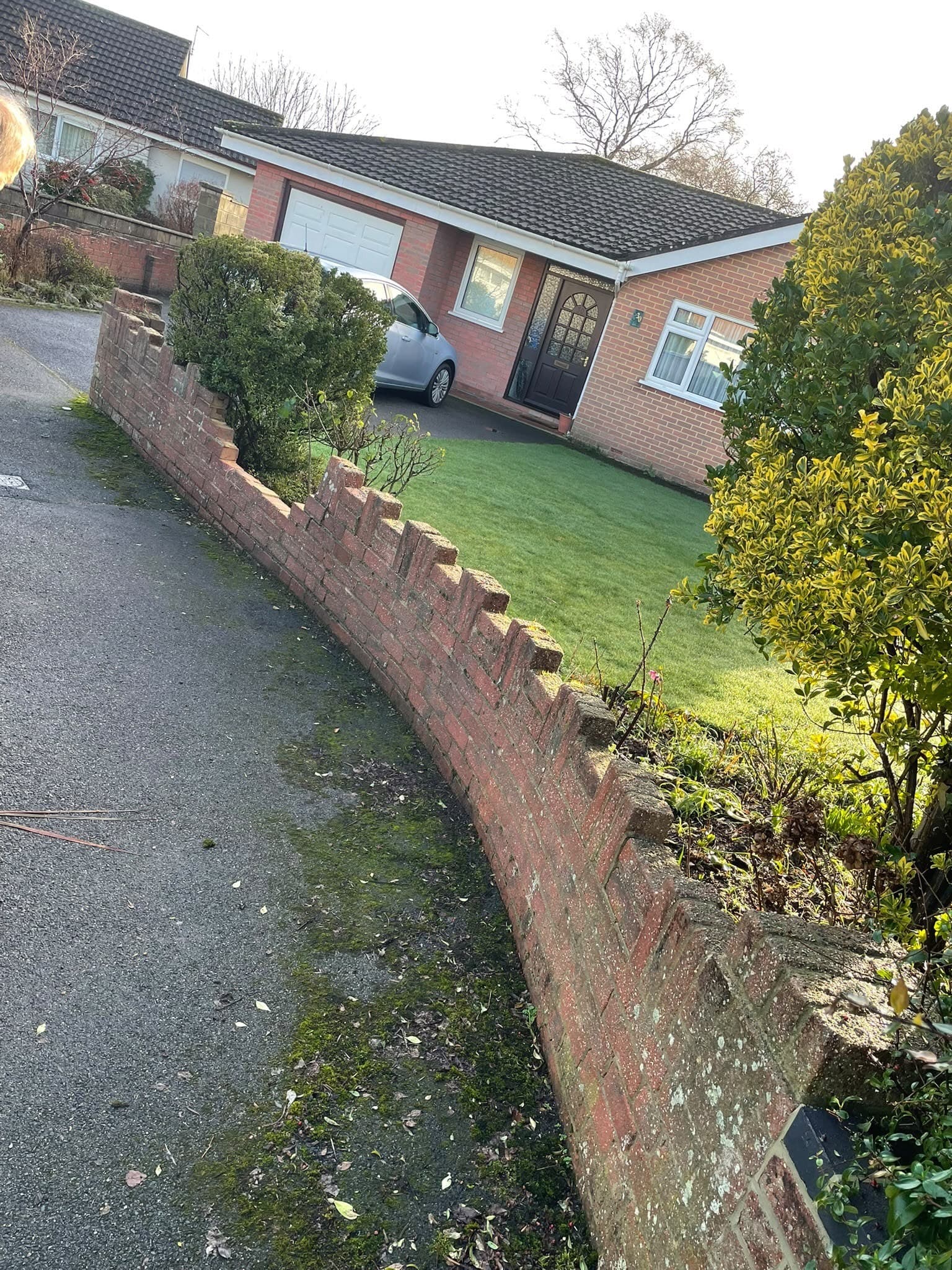 A weathered curved wall along a drive, before the brickwork was put right