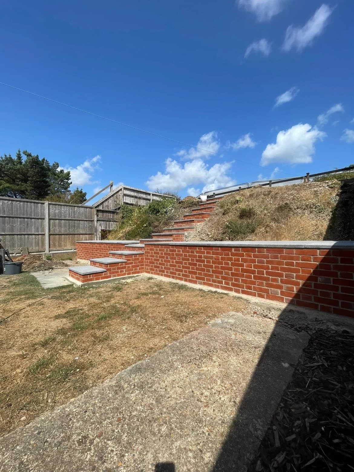 A brick retaining wall and steps cut into a garden bank