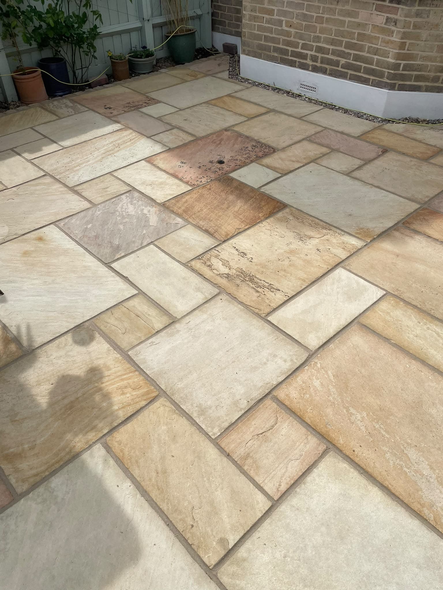 Buff sandstone paving turning the corner of a courtyard