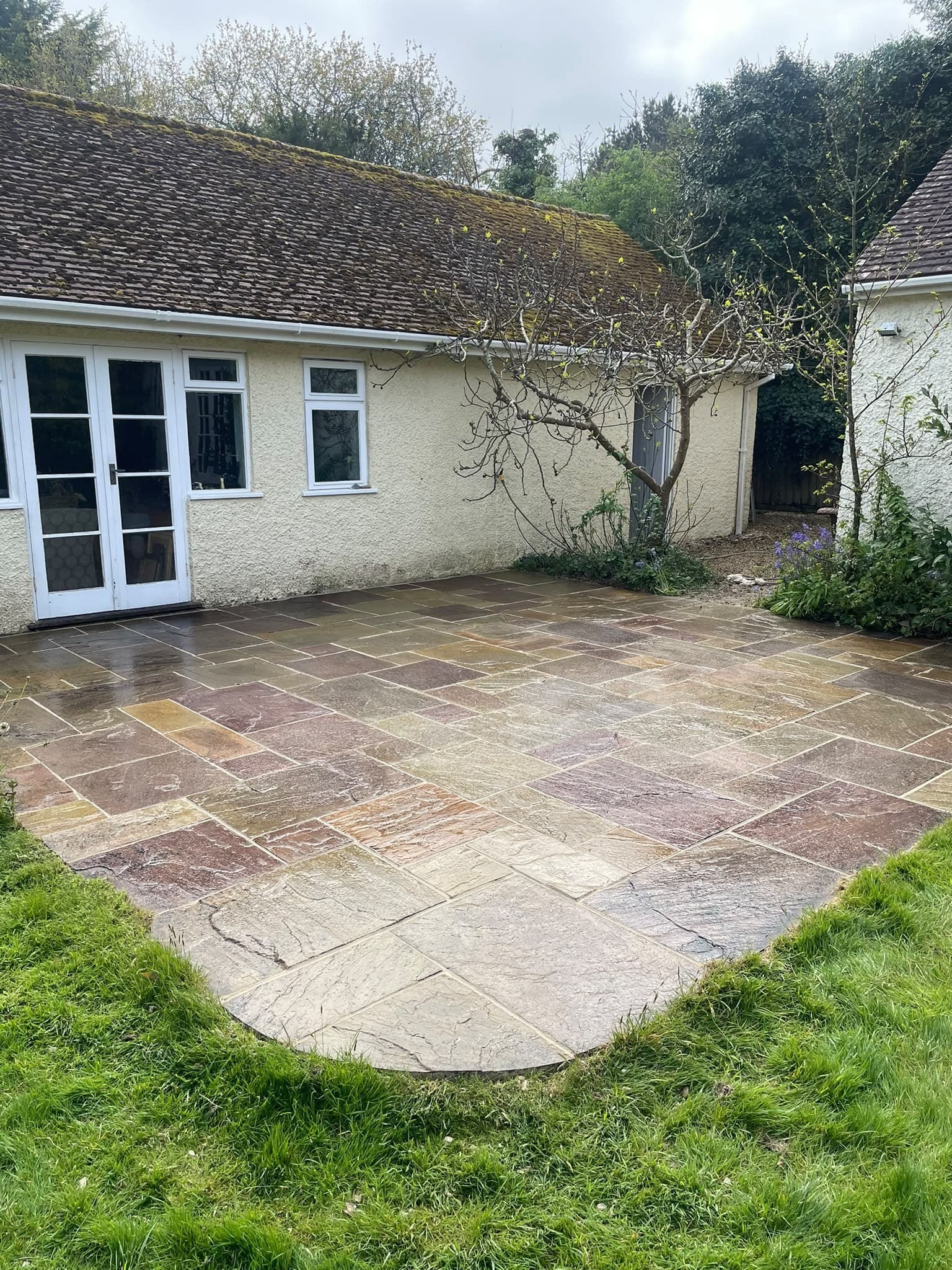 An Indian sandstone patio meeting the lawn behind a bungalow