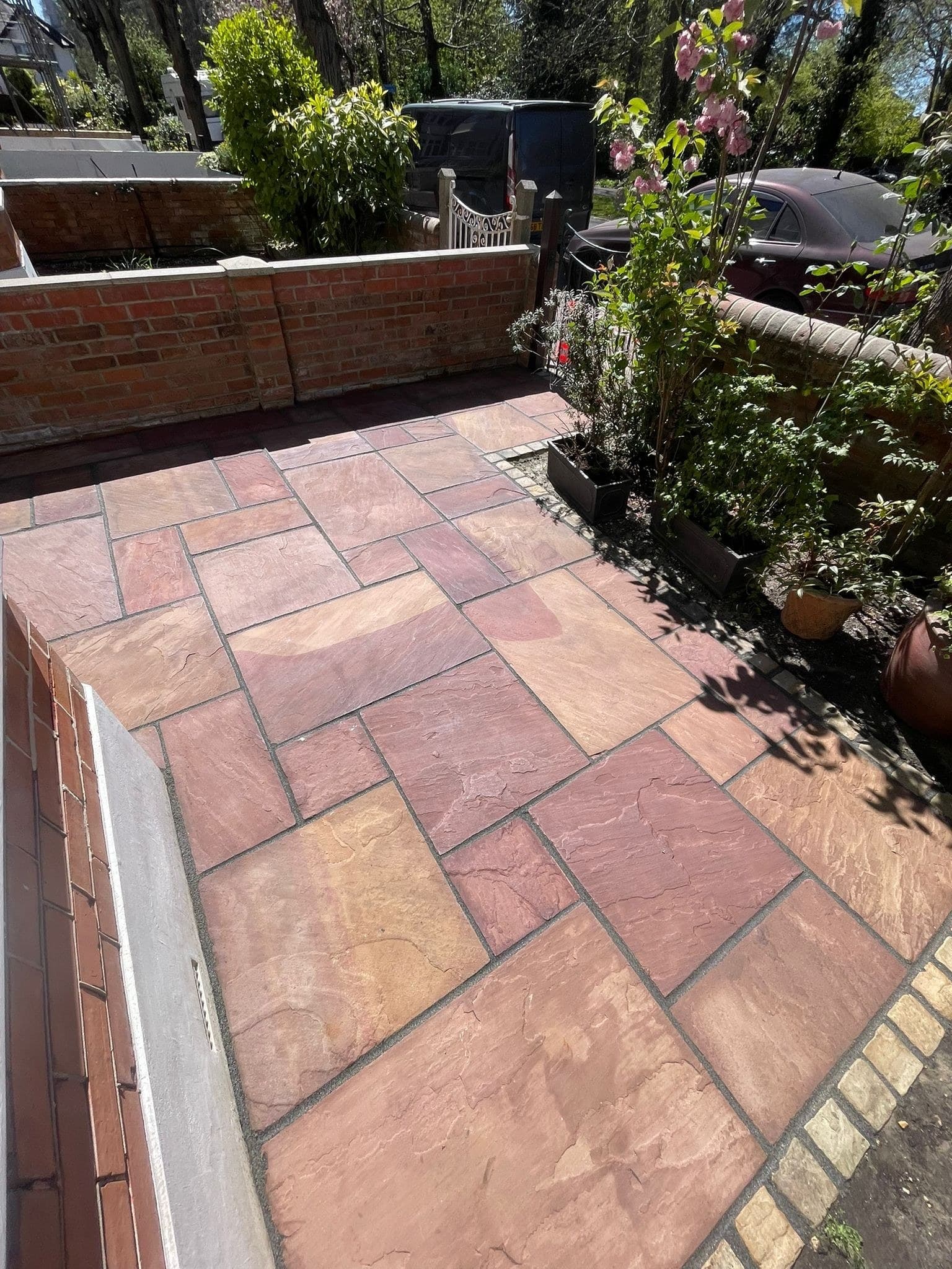A raised Indian sandstone patio held by a brick edge
