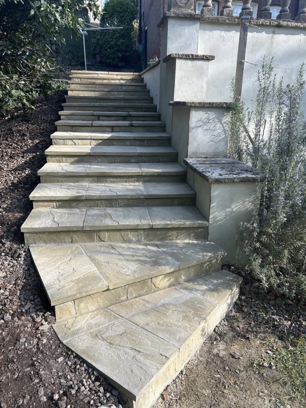 A flight of garden steps with slab treads beside a rendered wall
